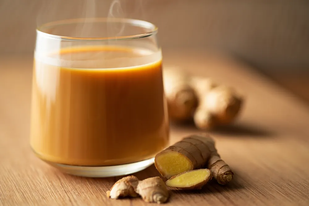 Glass of ginger chai with fresh ginger root