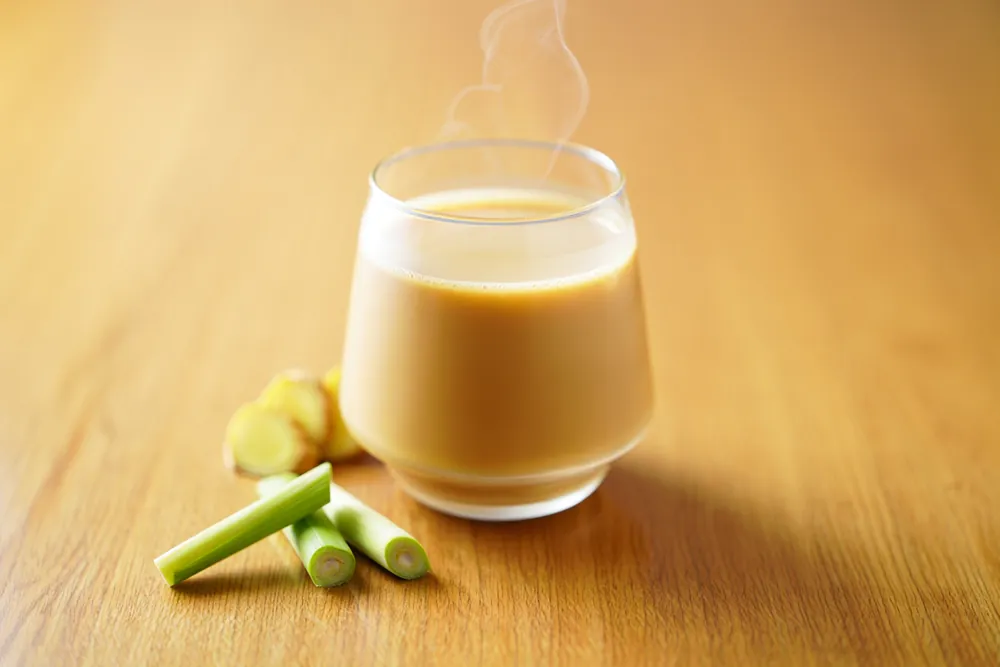 Glass of lemongrass chai with fresh lemongrass stalks and ginger